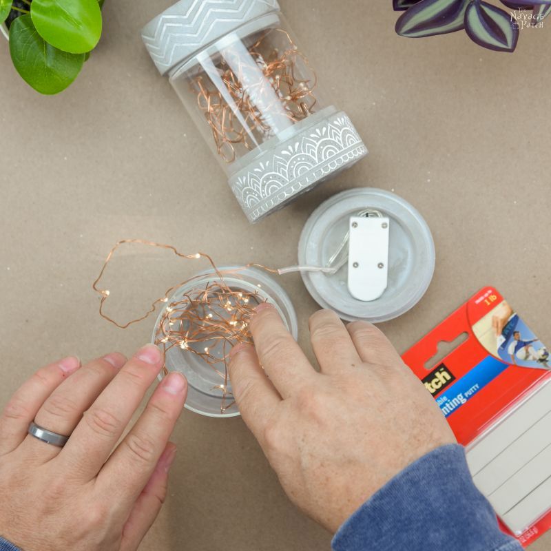 man stuffing string lights into a candle holder