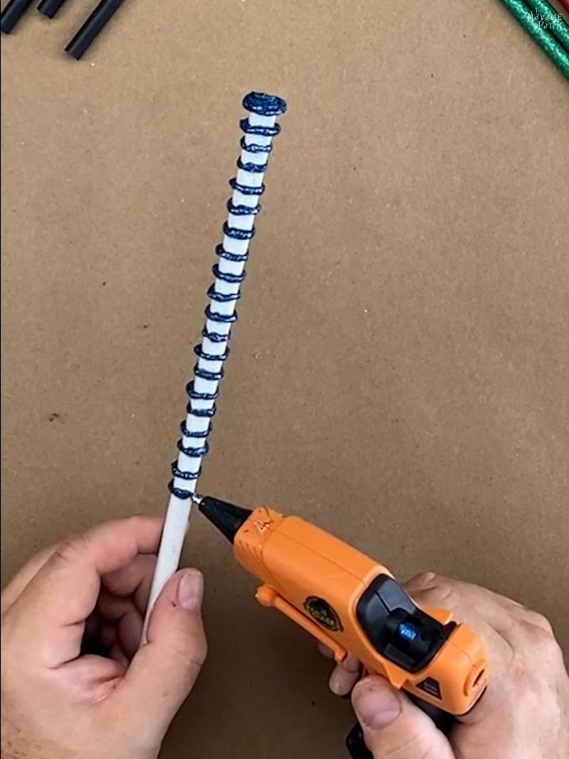 man putting blue glue rings around a white chopstick