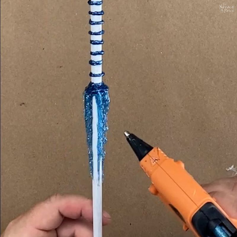 man putting blue glitter hot glue on a diy magic wand