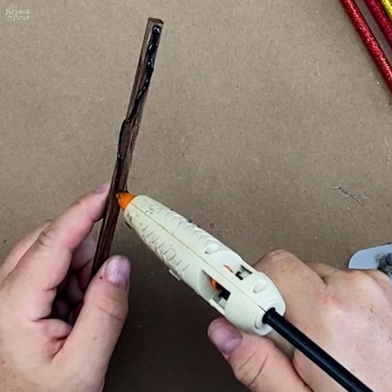 man putting black hot glue on a brown chopstick