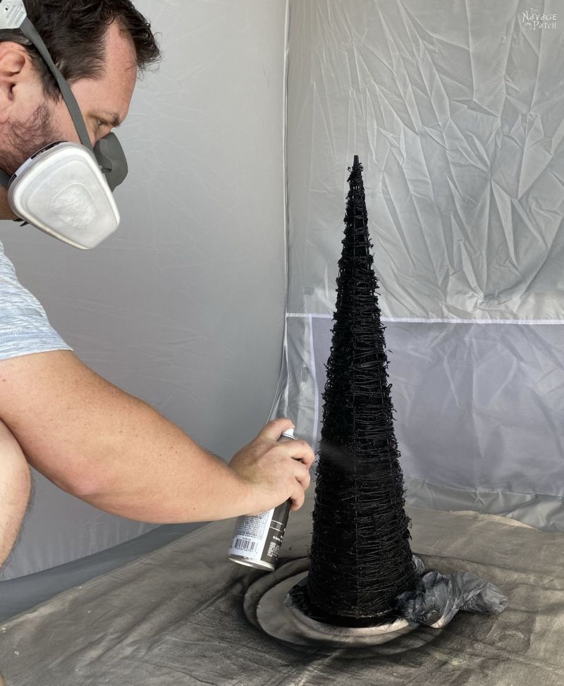 spraying a cone tree with black spray paint