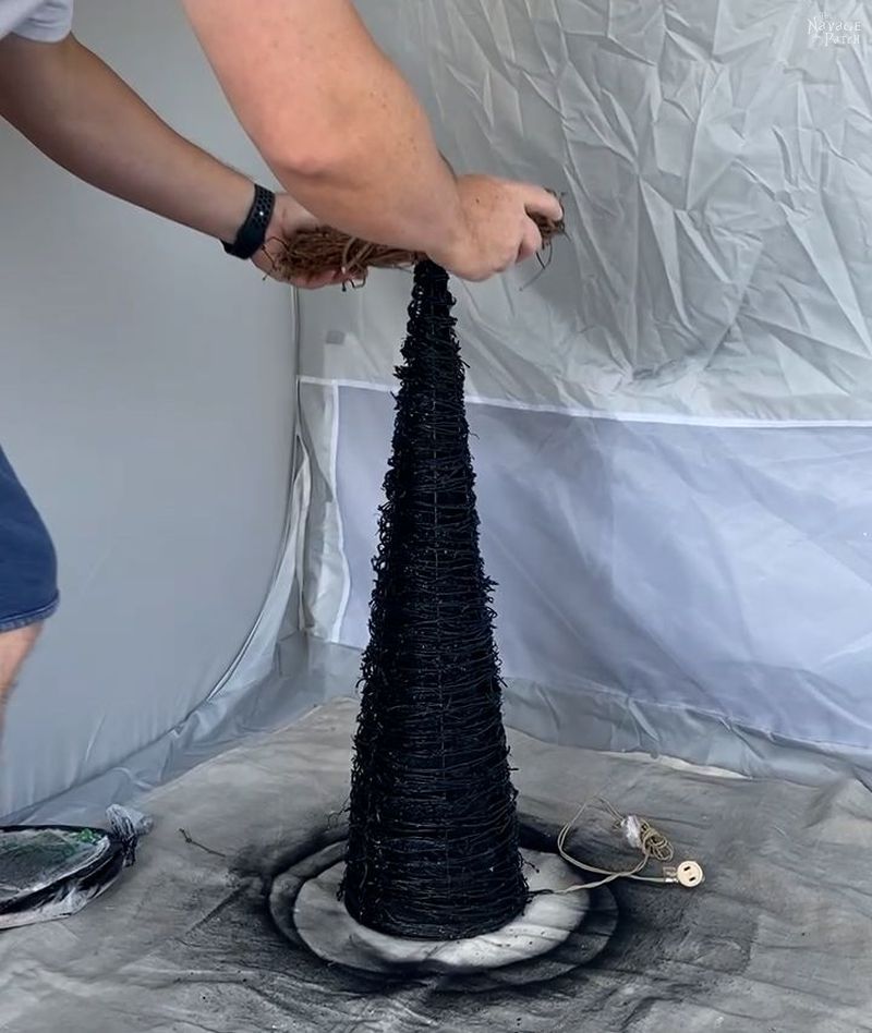 placing a grapevine wreath over a cone tree