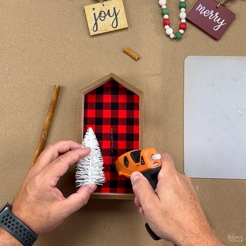man putting a line of hot glue in a shadow box