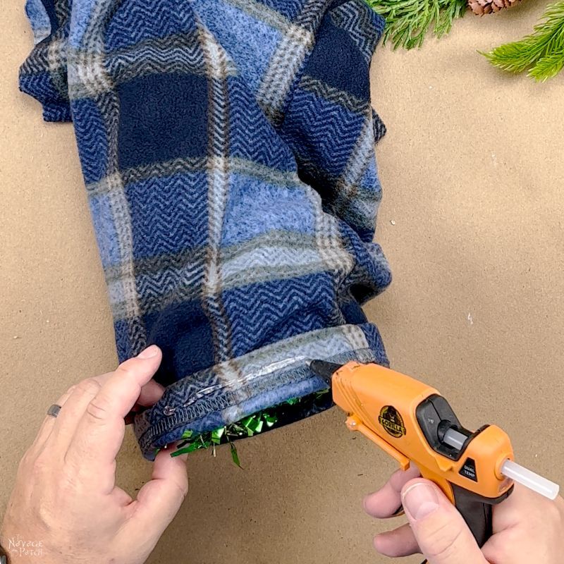 man gluing a pajama leg onto a tinsel tree