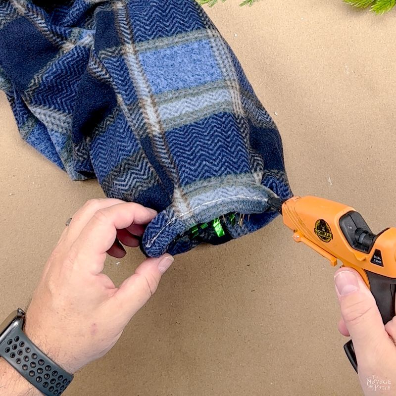 man gluing a pajama leg onto a tinsel tree