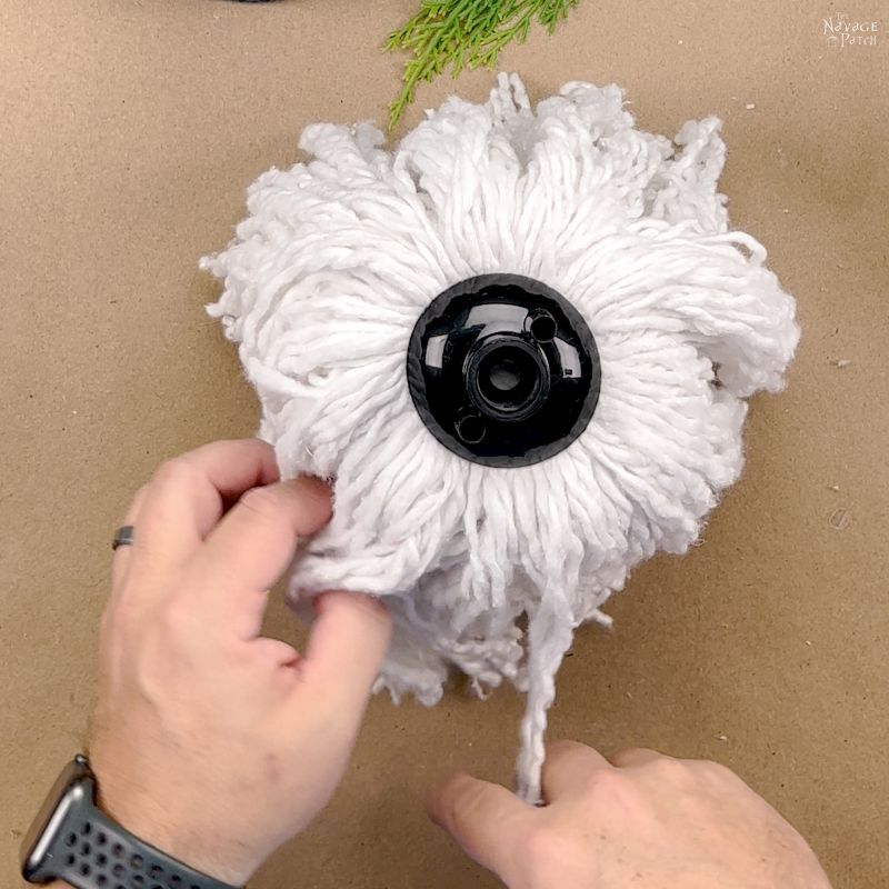 man straightening a mop head on a vase