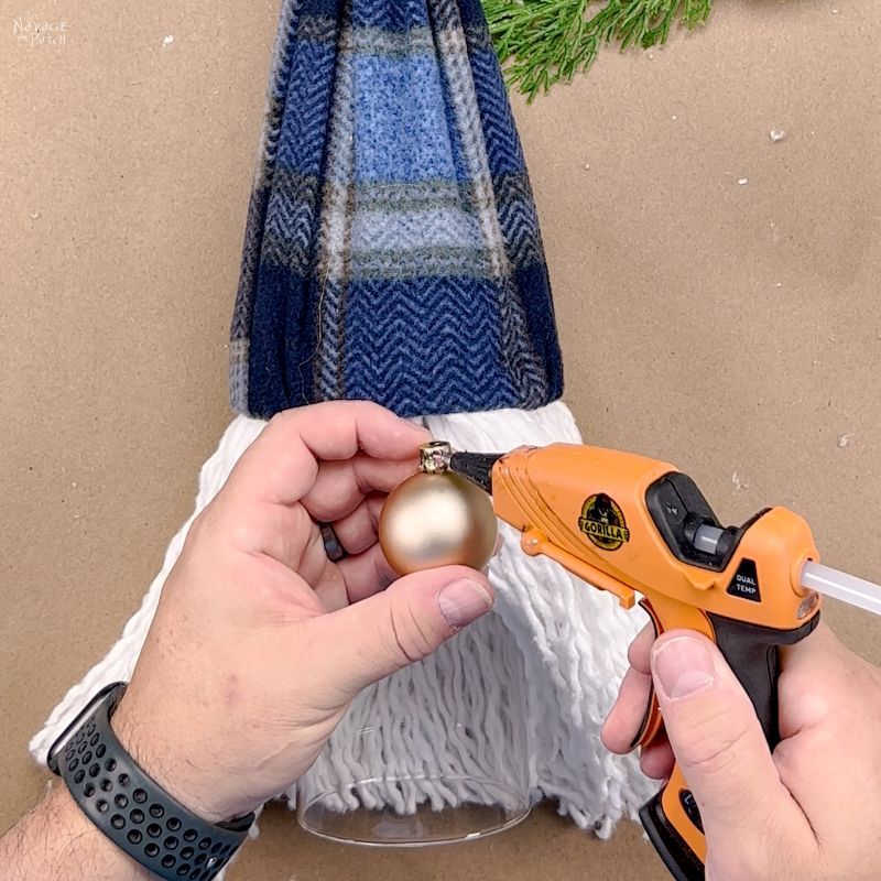 man putting hot glue on a christmas tree ornament