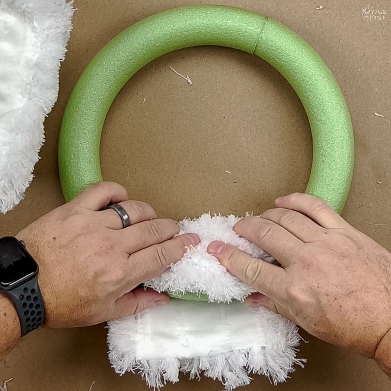 man gluing a dust mop onto a wreath form