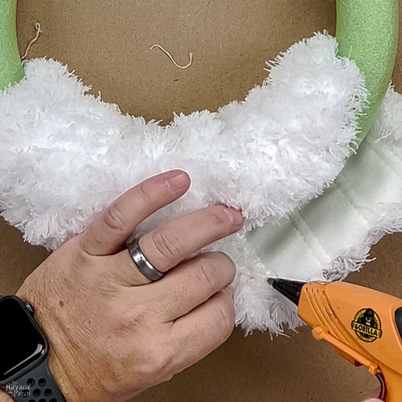 man gluing a dust mop onto a wreath form