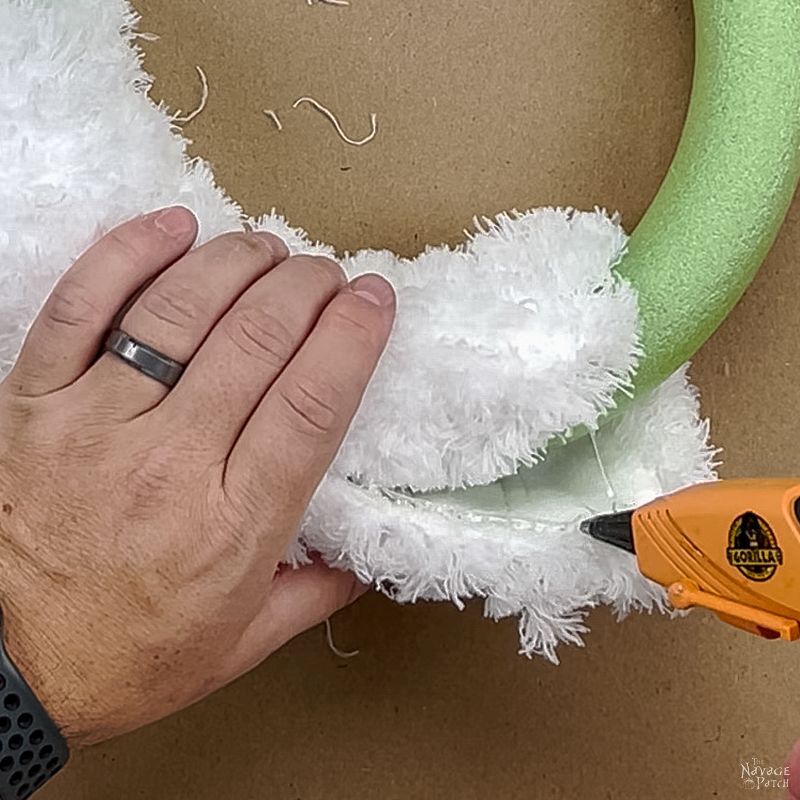 man gluing a dust mop onto a wreath form