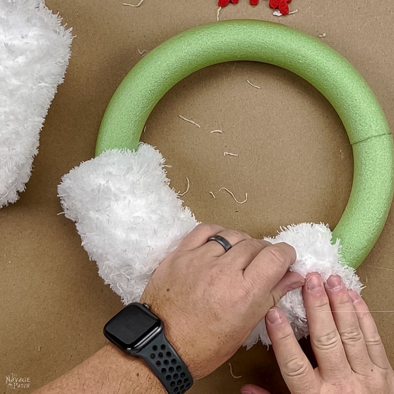 man gluing a dust mop onto a wreath form