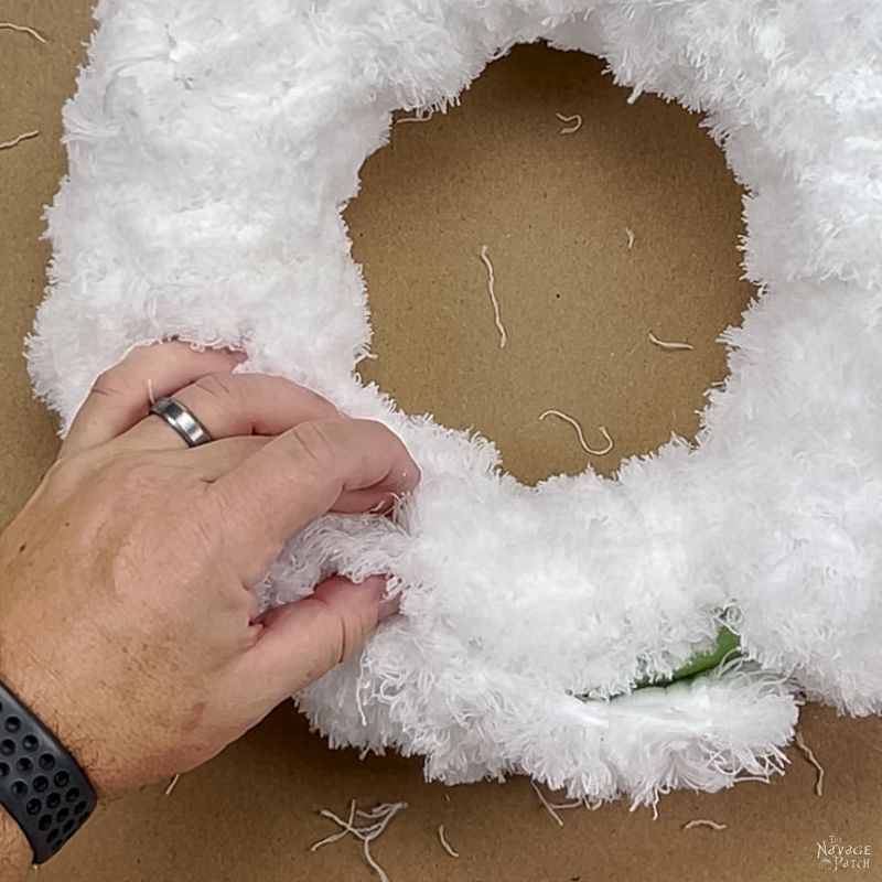 man gluing a dust mop onto a wreath form