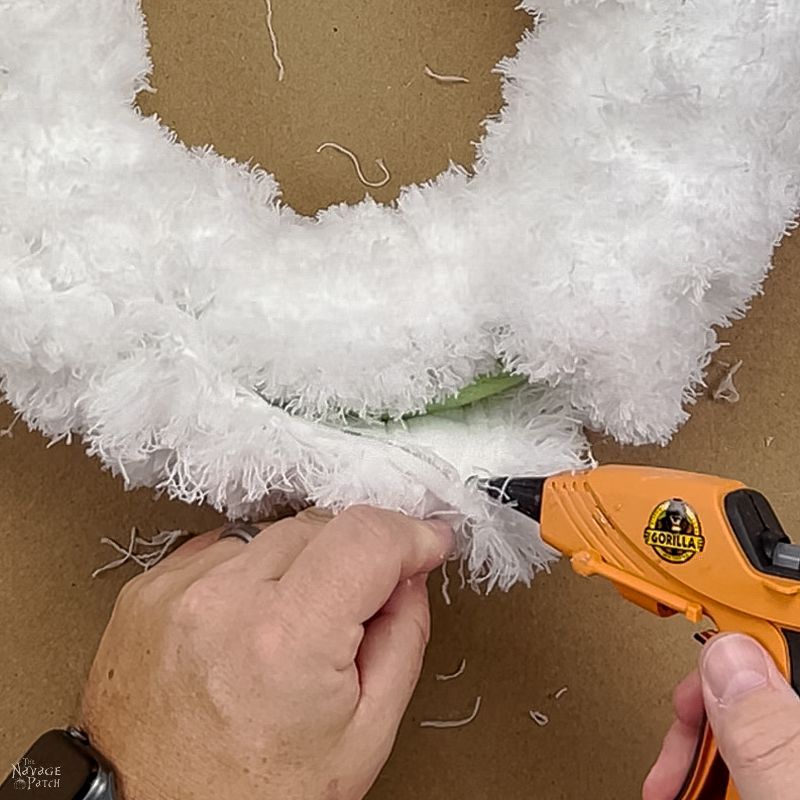 man gluing a dust mop onto a wreath form