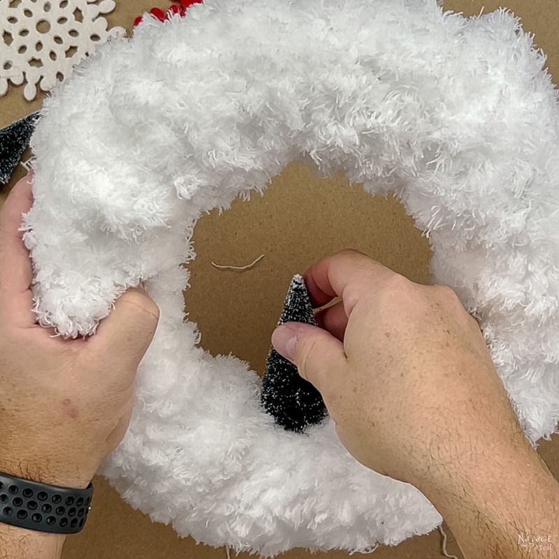 man gluing a bottle brush tree to a mop wreath