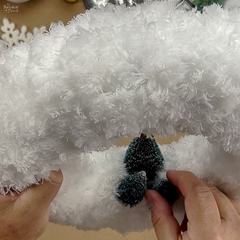 man gluing a bottle brush tree to a mop wreath