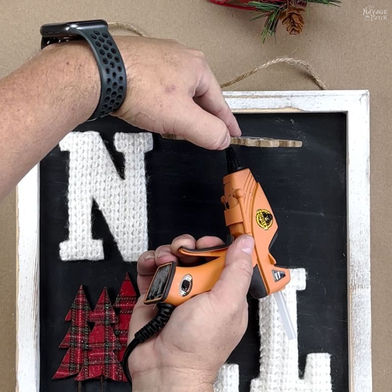 man gluing a wood snowflake to a sign