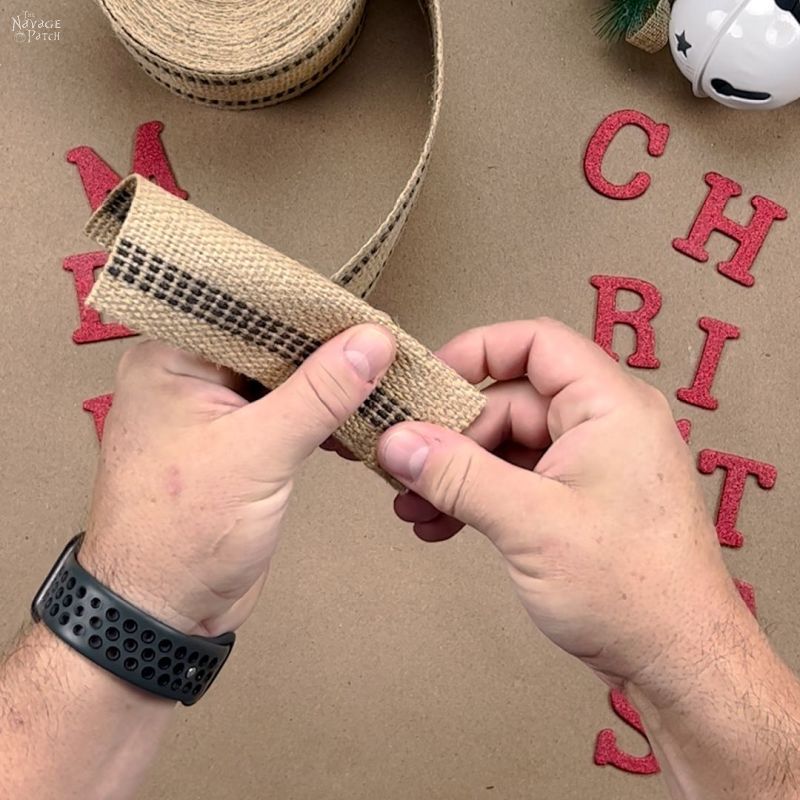 man folding a piece of burlap ribbon in half