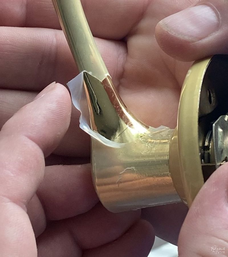 man peeling softened polyurethane from a brass door knob