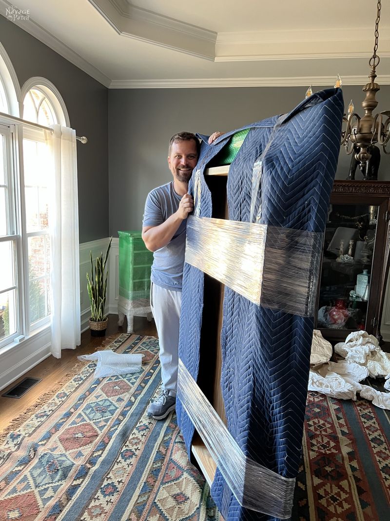 man holding a dining room table wrapped with moving blankets - how to pack for a move