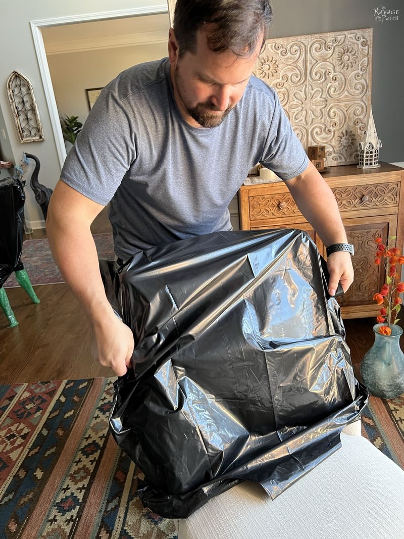 man placing a contractor bag over the back of a dining room chair