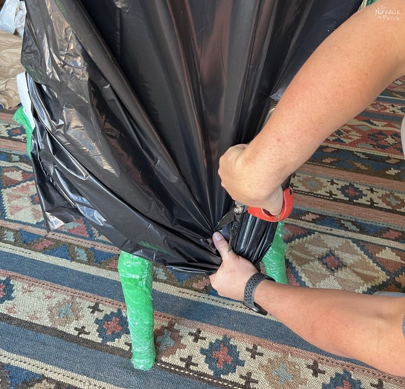 man cutting a contractor bag on a dining room chair