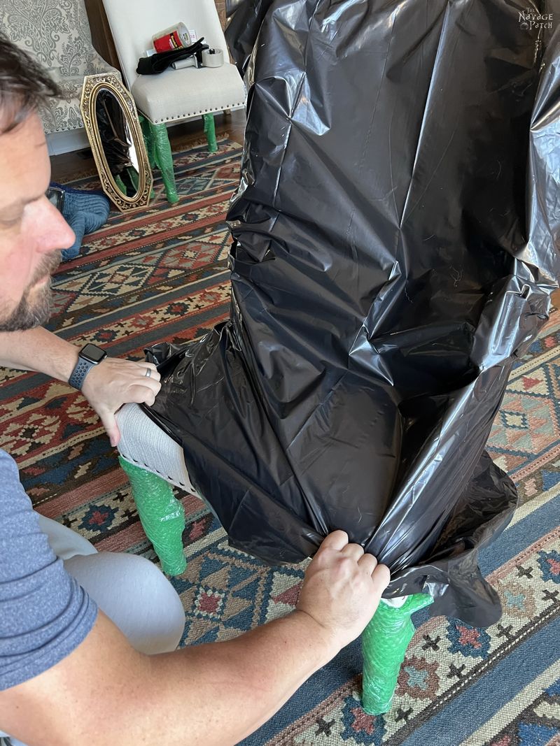 man pulling a contractor bag over a dining room chair