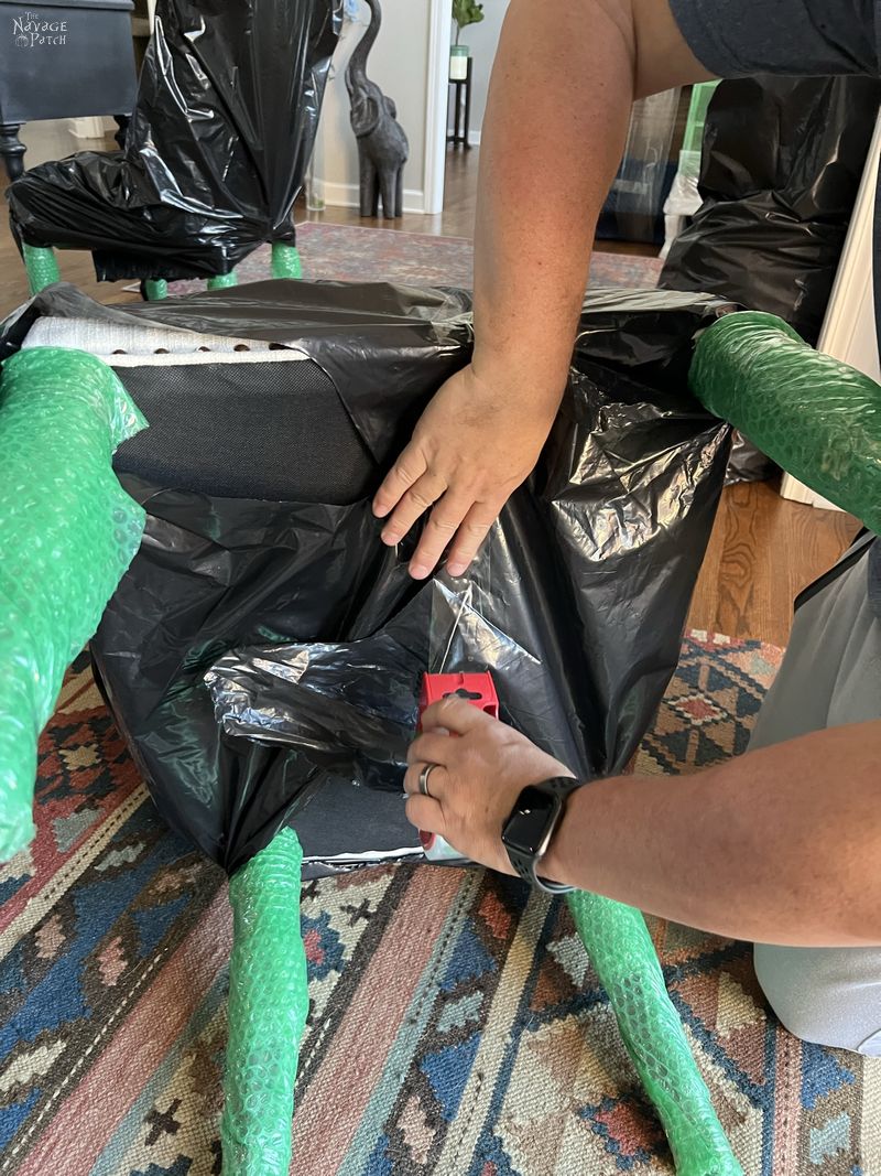 man taping a contractor bag onto a dining room chair