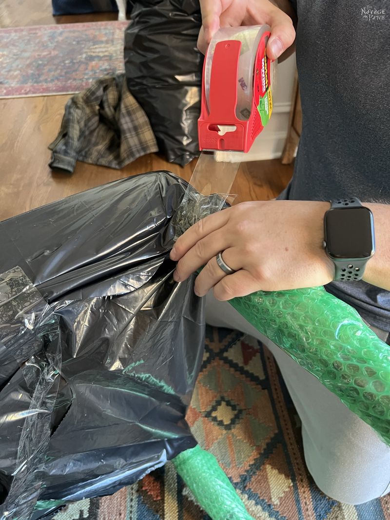 man taping a contractor bag to the bubble wrap on a chair leg - how to pack for a move