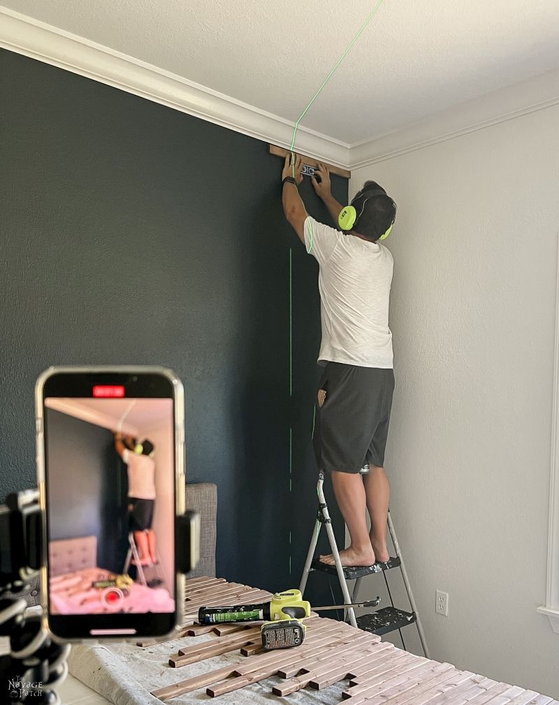 man installing wood slats on an accent wall