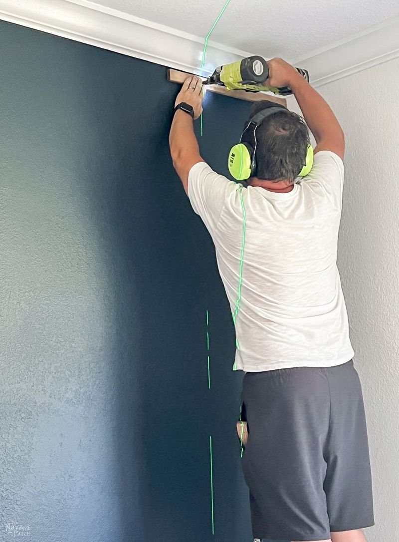 man installing wood slats on an accent wall