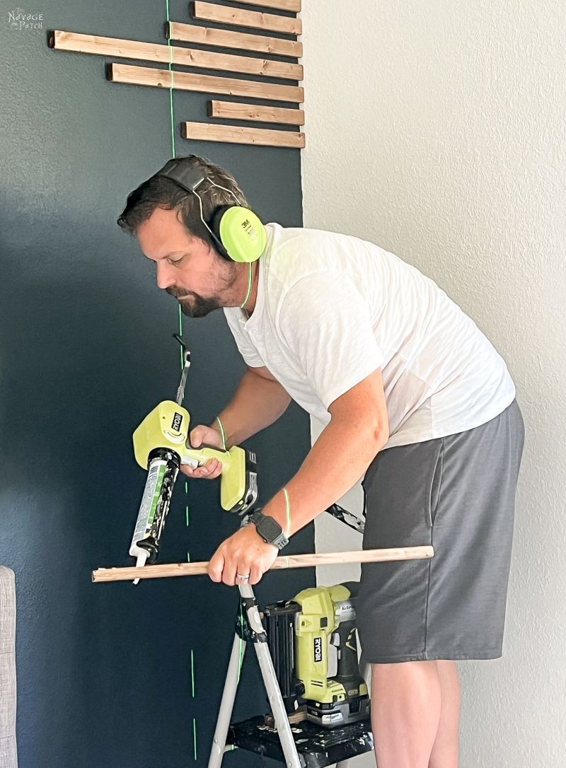 man installing wood slats on an accent wall