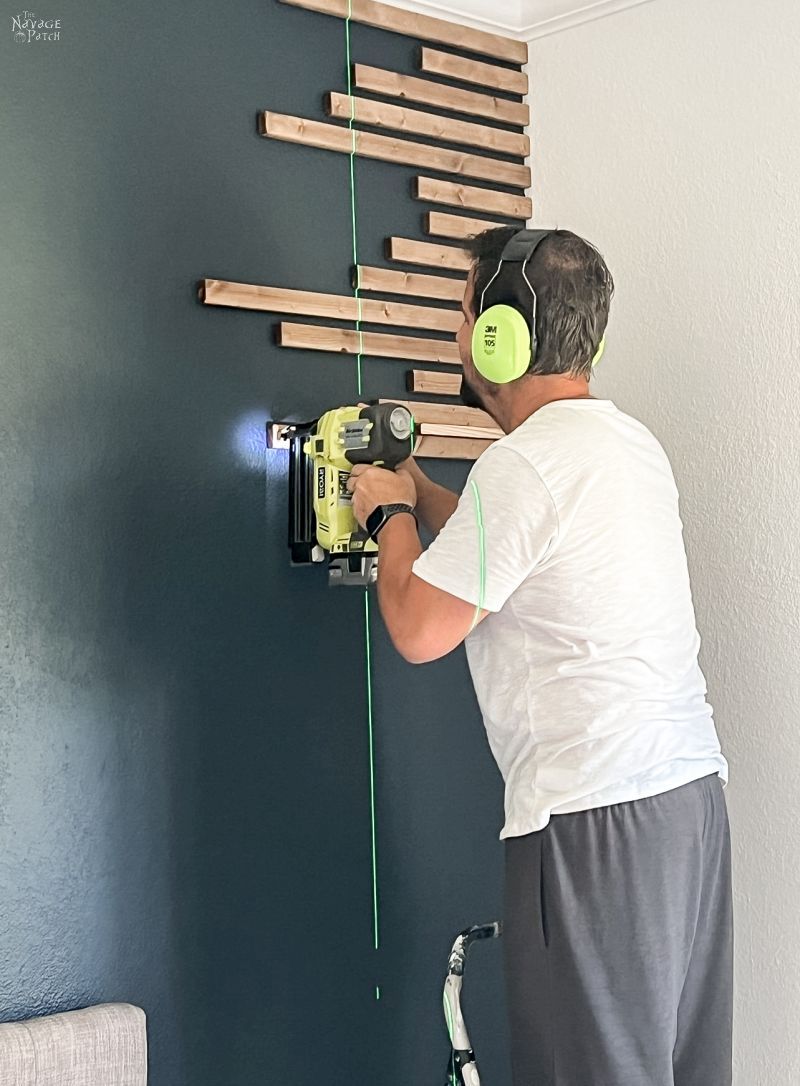 man installing wood slats on an accent wall