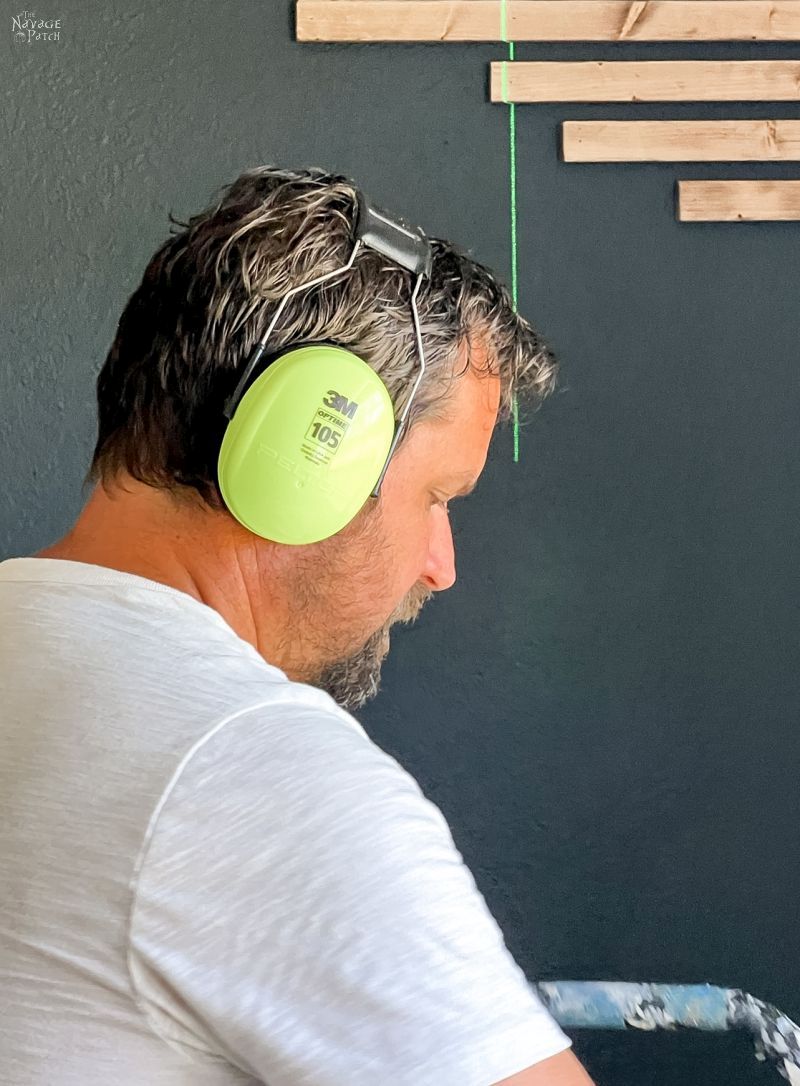 man installing wood slats on an accent wall