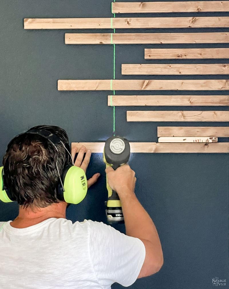 man installing wood slats on an accent wall