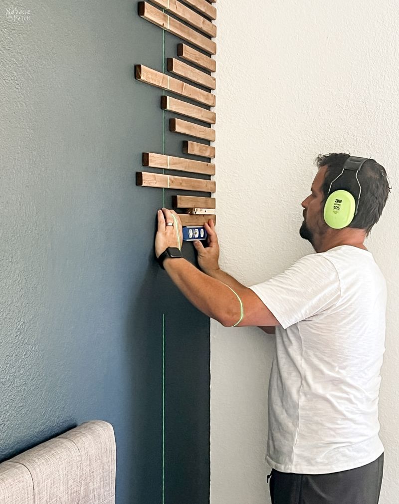 man installing wood slats on an accent wall