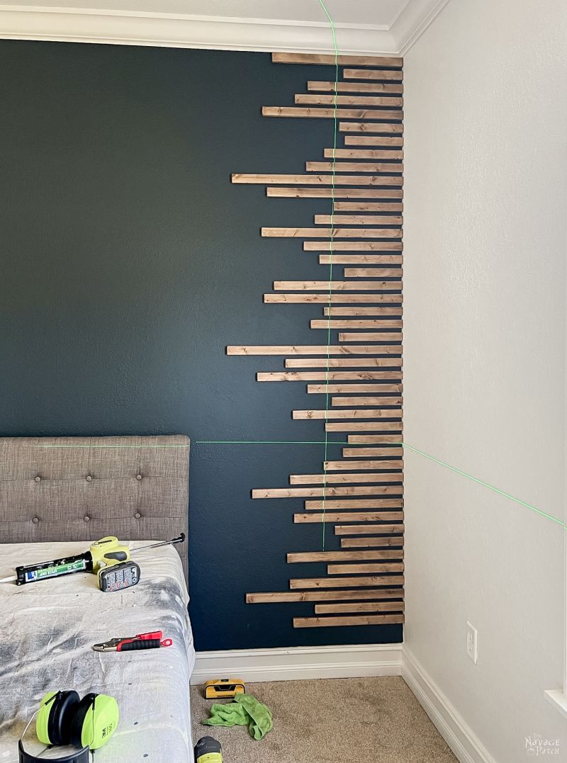 man installing wood slats on an accent wall