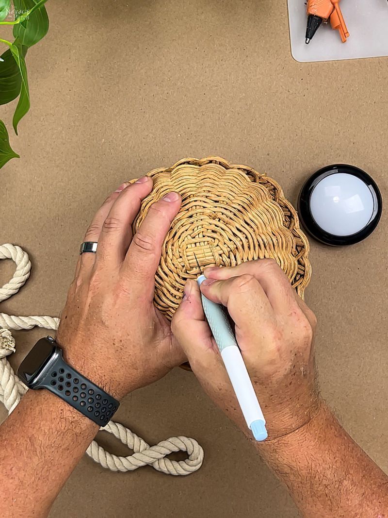 man cutting a hole in a rattan basket