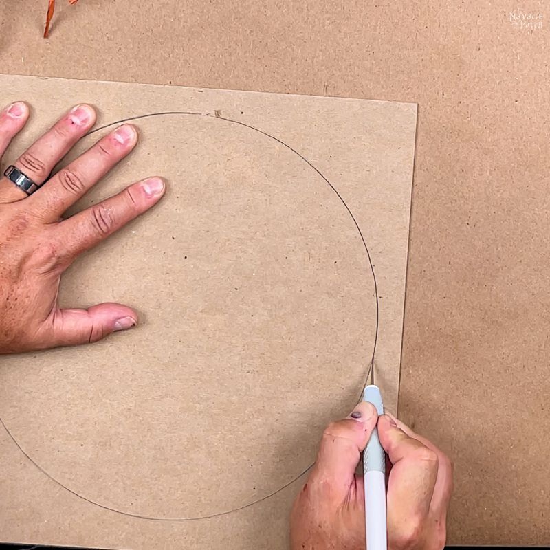 man cutting a circle from cardboard with an x-acto knife