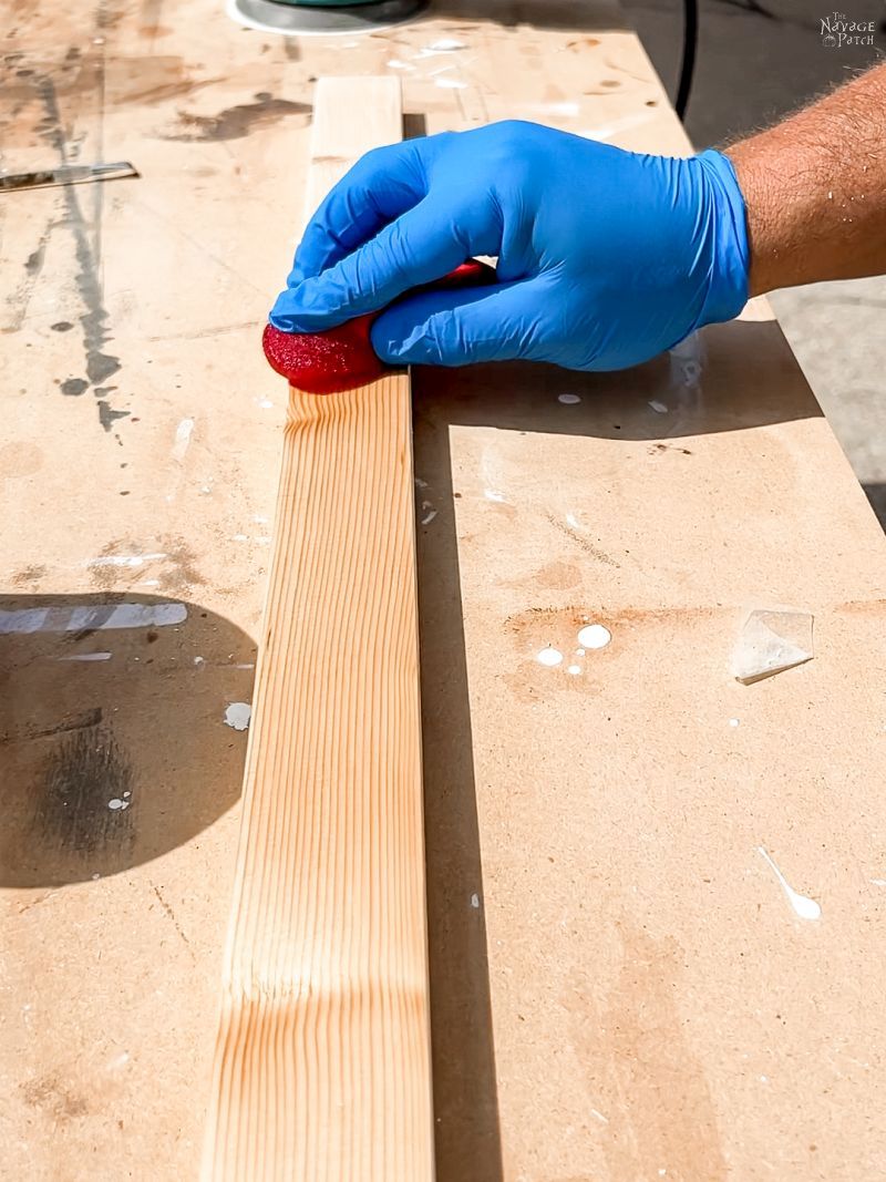 man applying pre-stain to pine boards