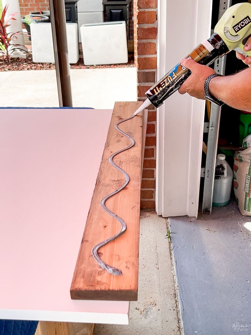 man putting adhesive on the back of a board to make a diy sliding barn door