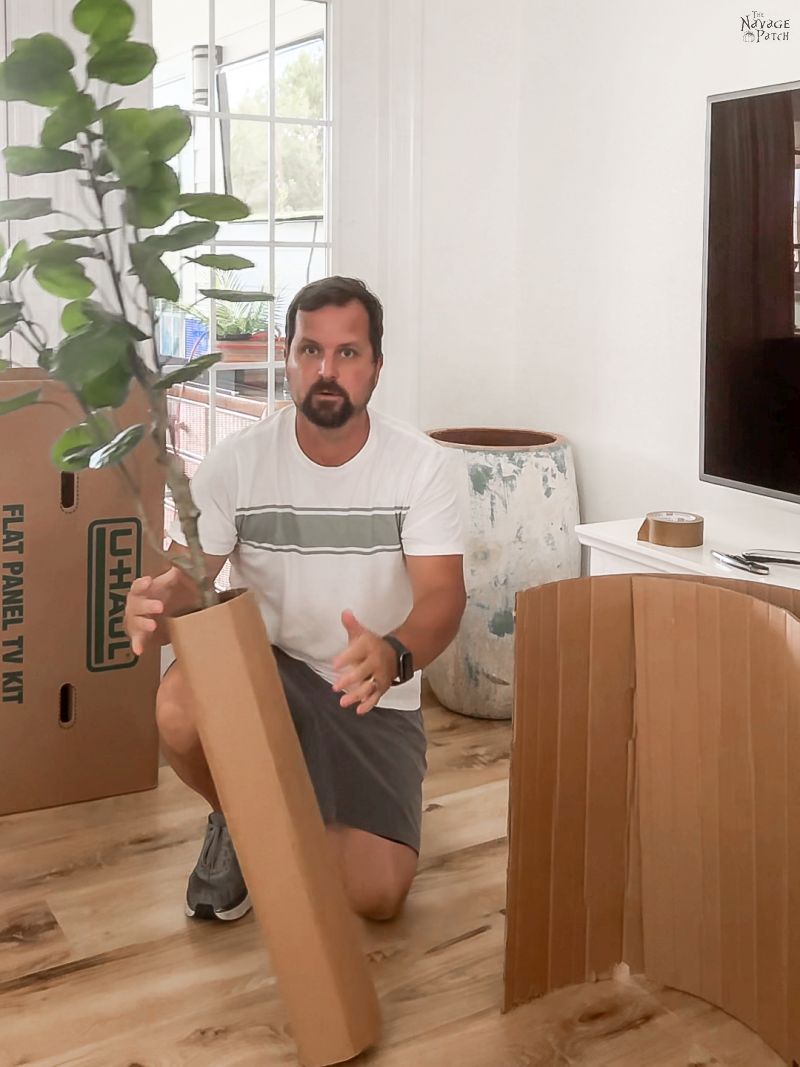 man holding cardboard cylinder with plant inside