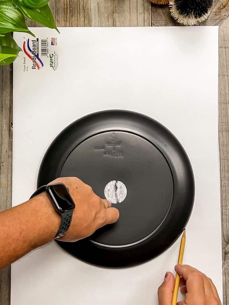 man tracing a circle onto foam board with dinner plate