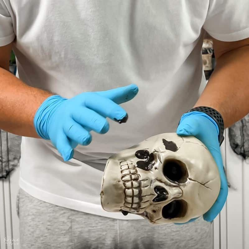 man staining plastic skulls for halloween chandelier