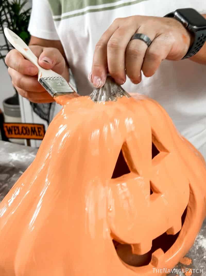 man painting a plastic pumpkin