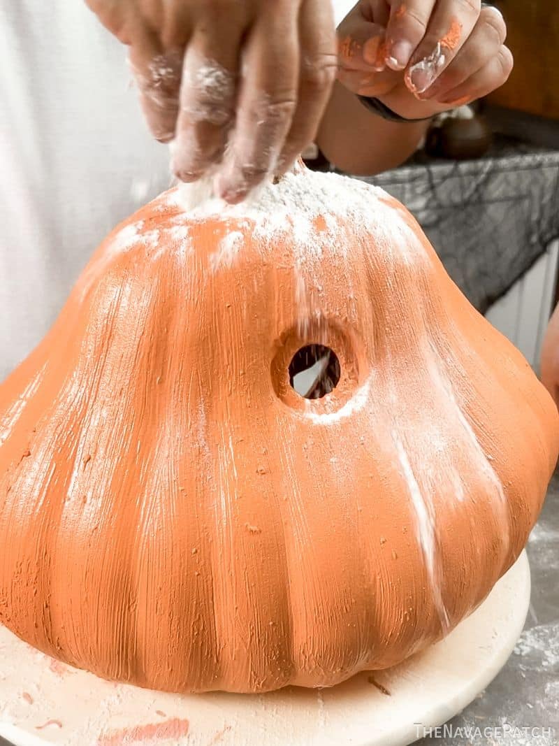 man sprinkling flour on a painted pumpkin
