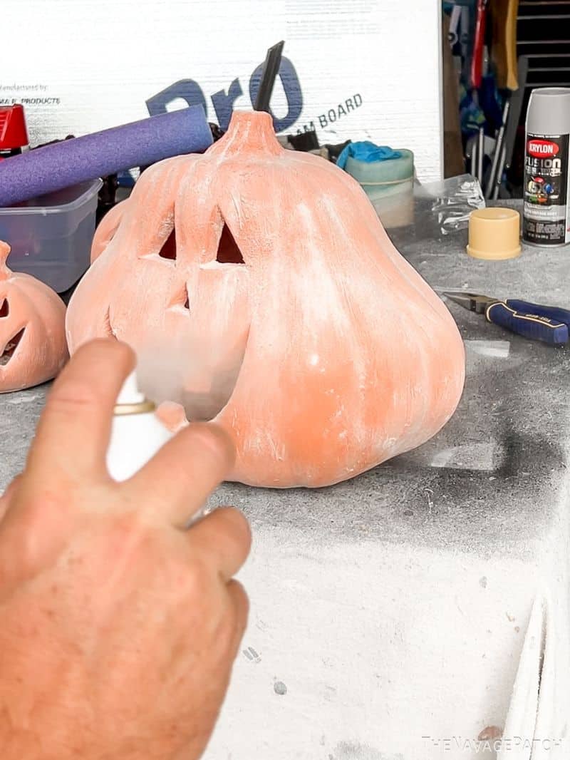 man spraying terracotta pumpkins with fixatif