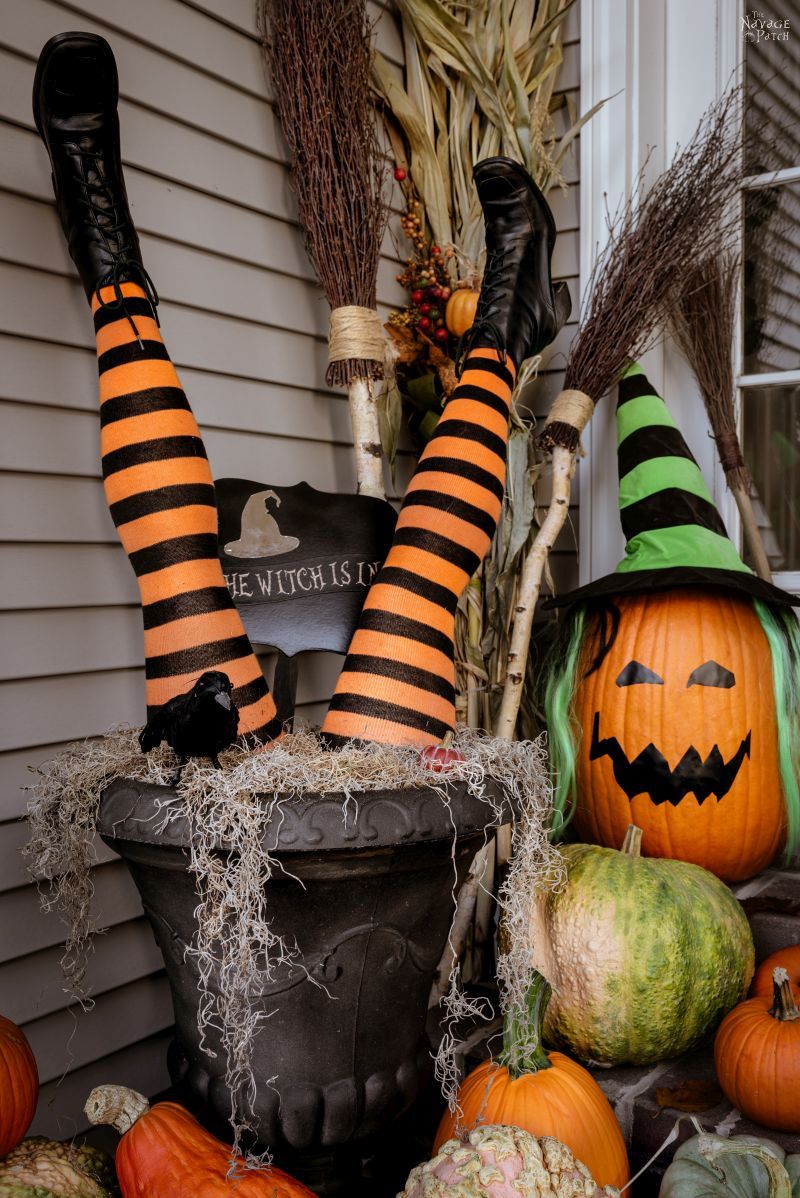 DIY Witch Legs in an urn surrounded by pumpkins on a front porch