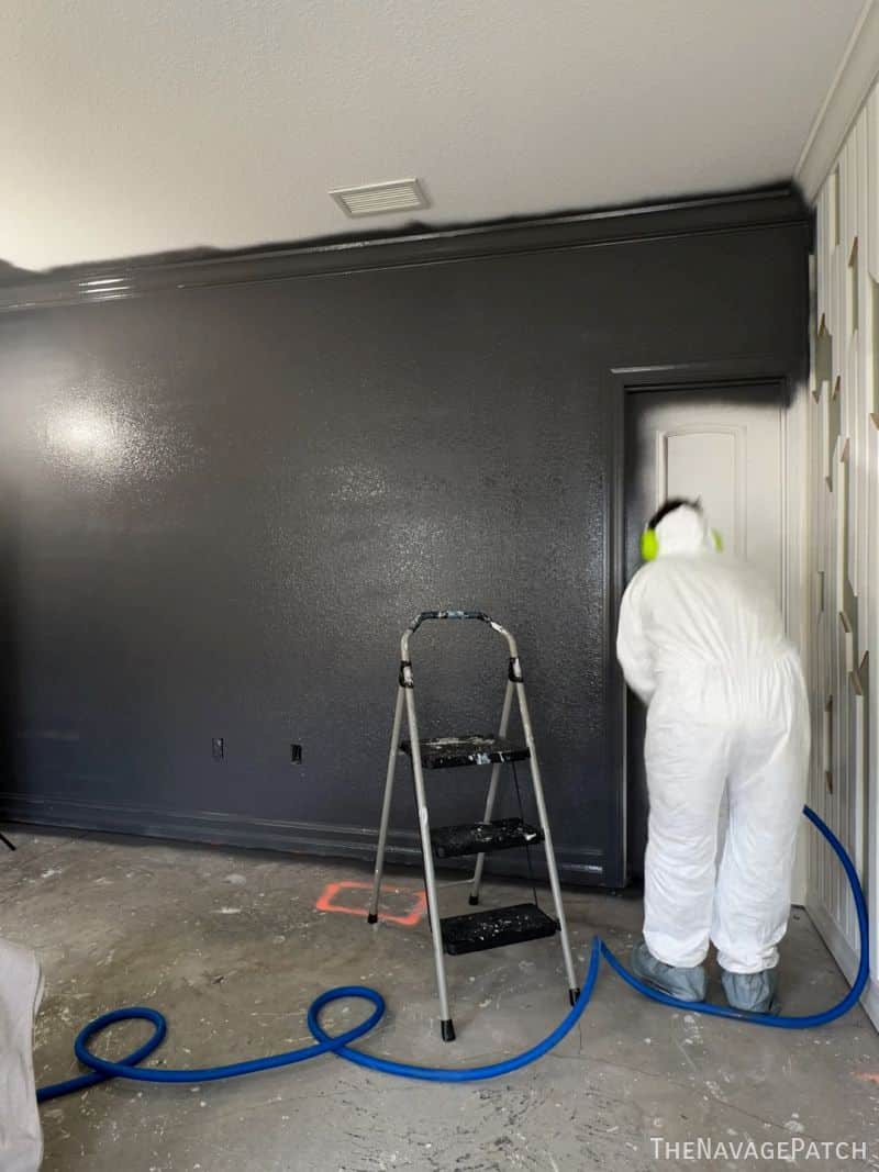man painting walls with a sprayer
