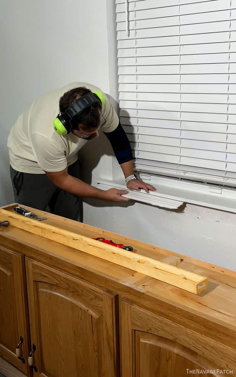 man removing trim from a window