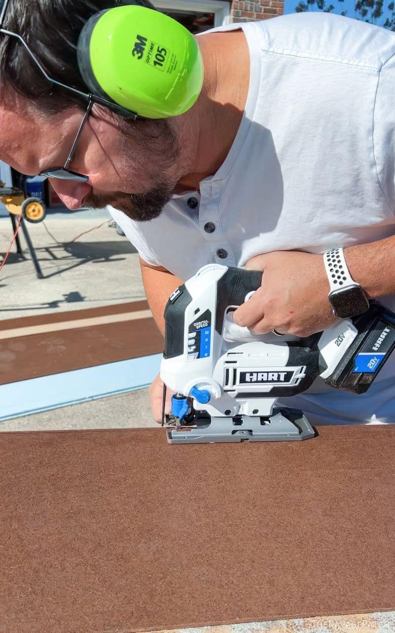 man cutting hardboard with a jigsaw